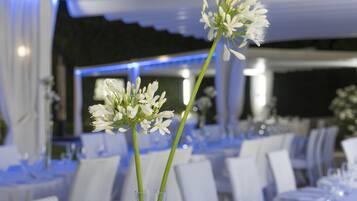 Un comedor con mesas dispuestas para un evento formal, con manteles blancos y sillas.
