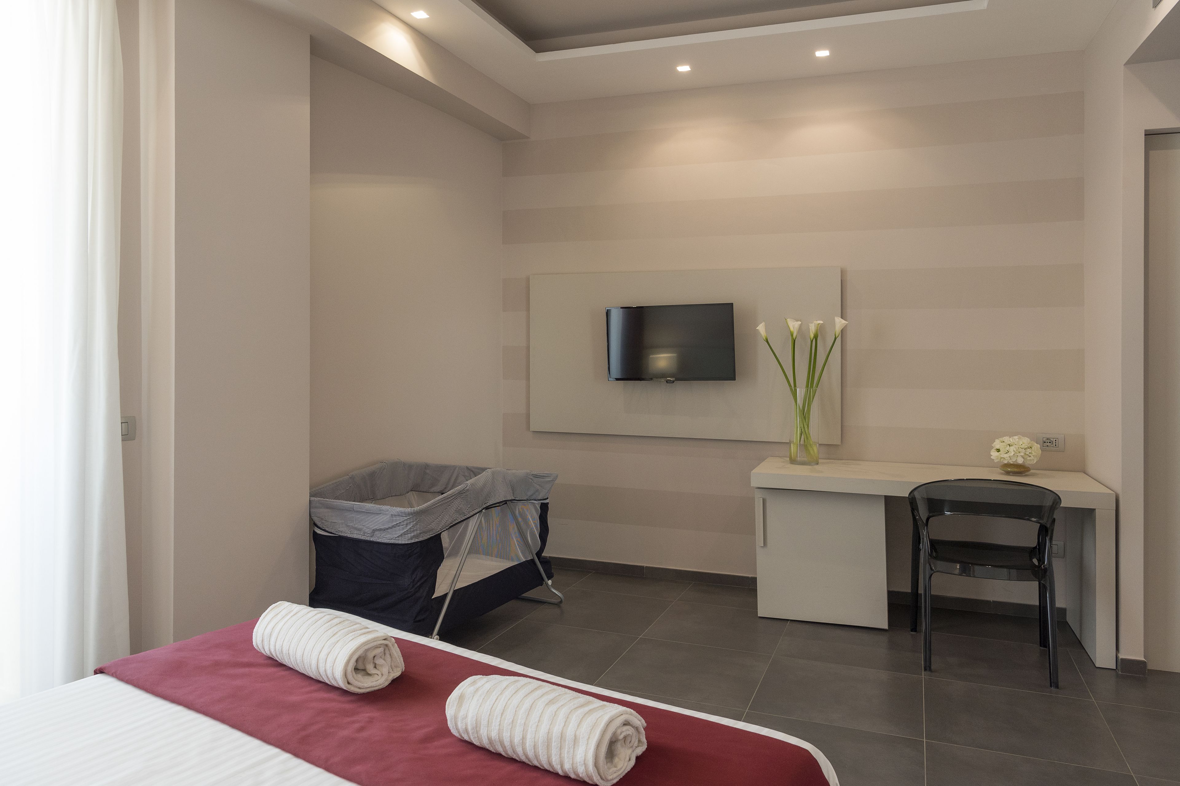 Una habitación de hotel moderna con una cama, un escritorio, una silla, un televisor y un bote de basura.