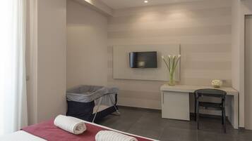 Una habitación de hotel moderna con una cama, un escritorio, una silla, un televisor y un bote de basura.
