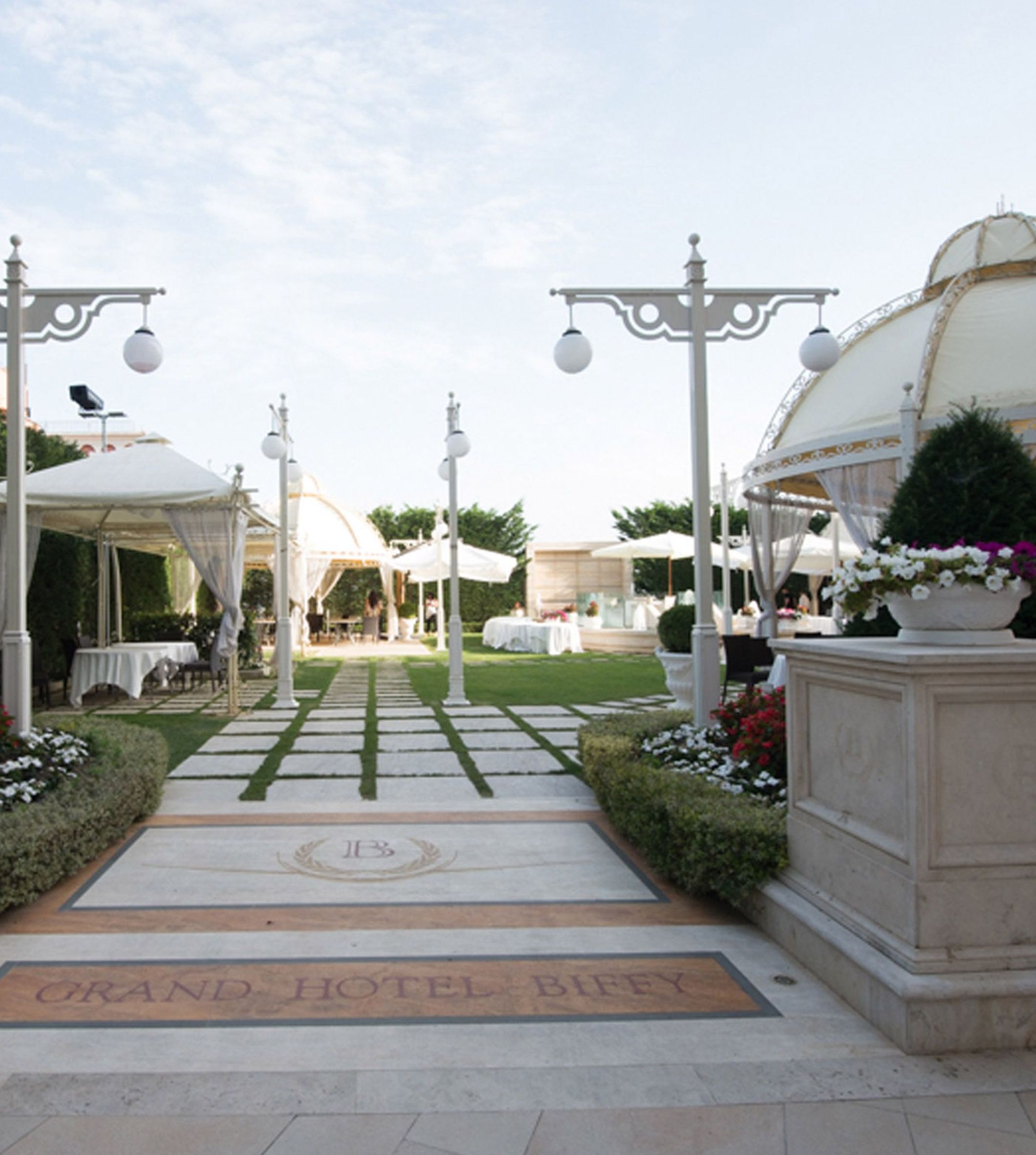 Une grande entrée d’hôtel, avec un chemin pavé menant à une zone abritée.