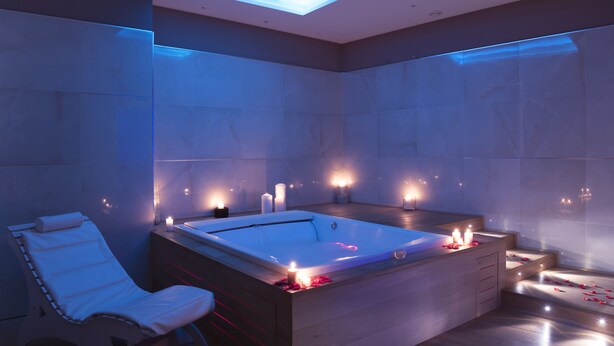 A modern bathroom with a freestanding bathtub, a massage chair, and candles.
