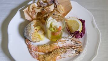 Un plato con mariscos, incluyendo camarones, calamares y una rodaja de limón.