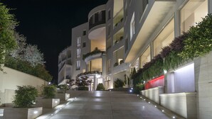 A modern hotel with a curved facade, multiple balconies, and a well-lit entrance.