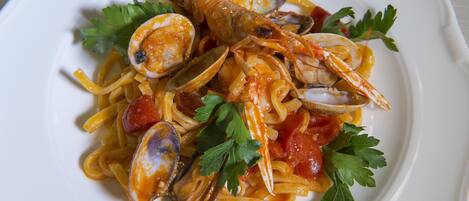 Un plato de pasta con almejas y tomates, adornado con perejil.