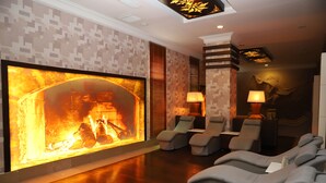 Un espacio de spa con una chimenea grande empotrada, asientos acolchados e iluminación ambiental.