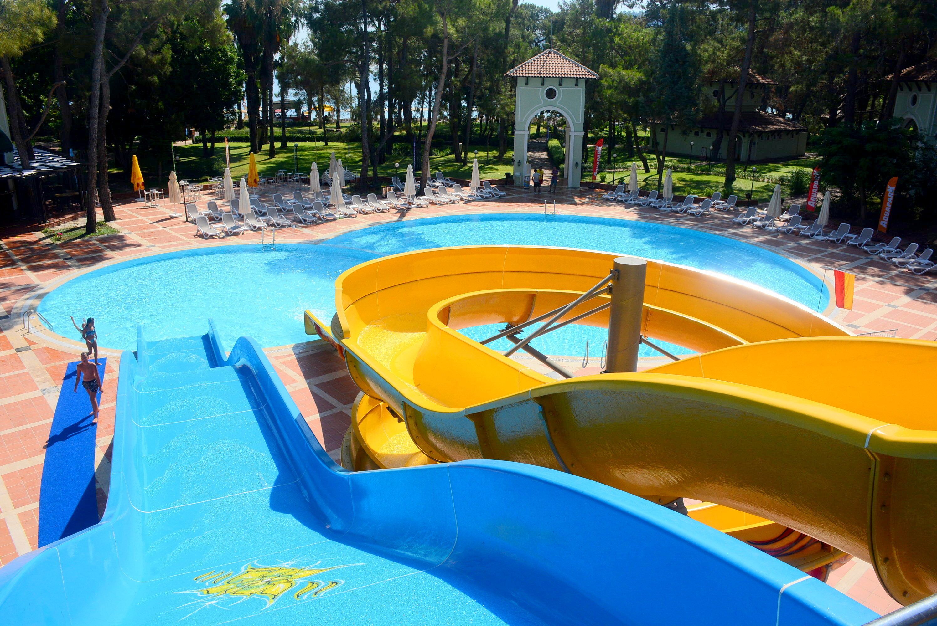 A water park with a large pool, two water slides, and lounge chairs.