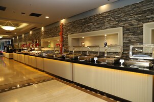 A buffet area with multiple food stations, a stone wall, and a long counter with various dishes.