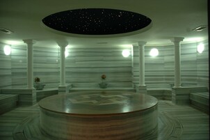 Una habitación circular con techo estrellado, paredes de mármol y columnas.