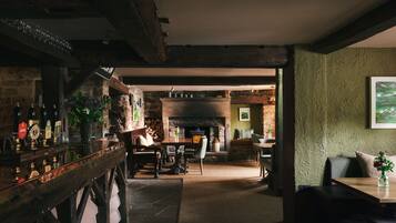 Un interior rústic amb zona de bar, seients i una llar de foc.