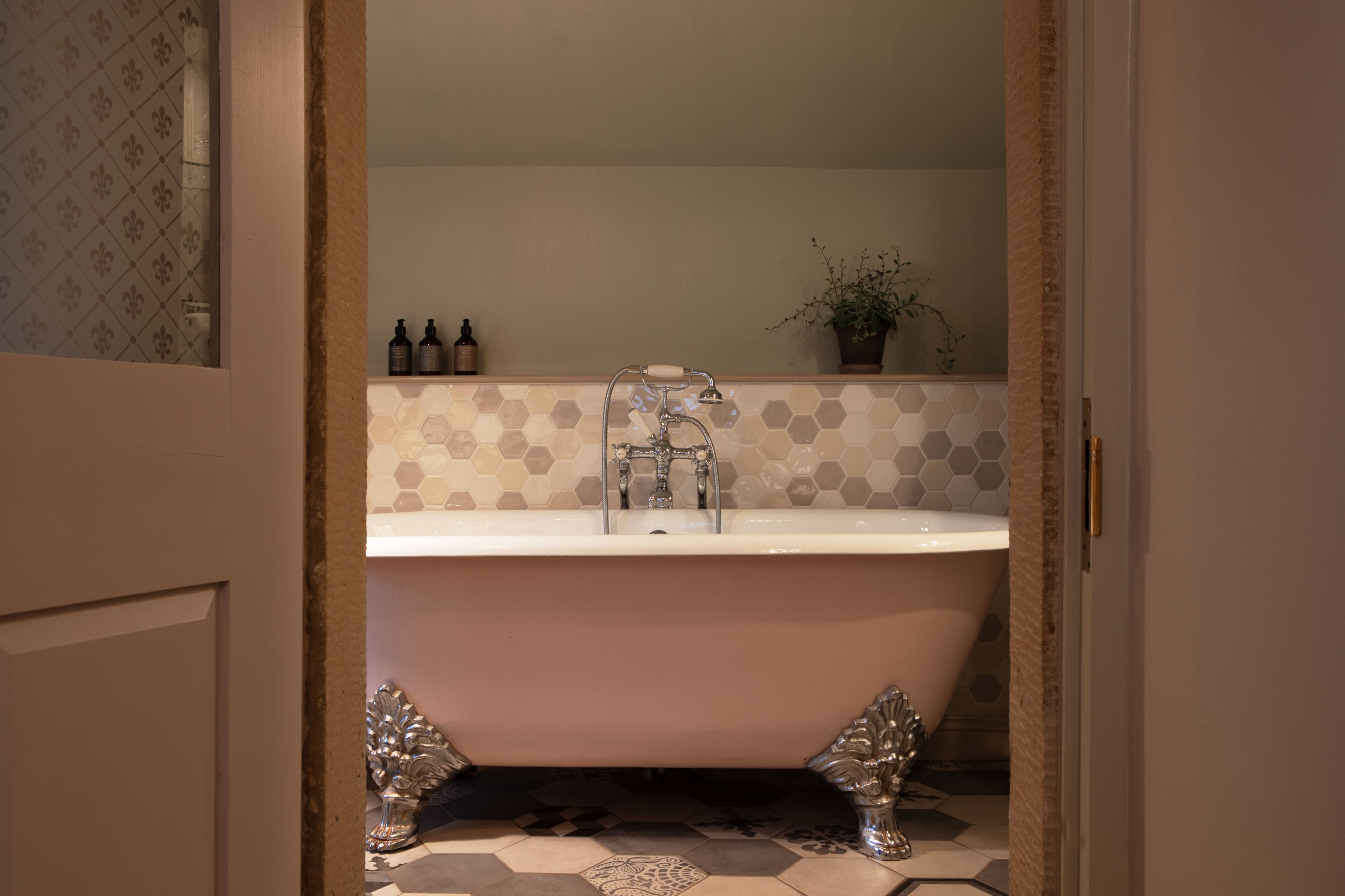 A bathroom with a freestanding bathtub, a sink, and a potted plant.