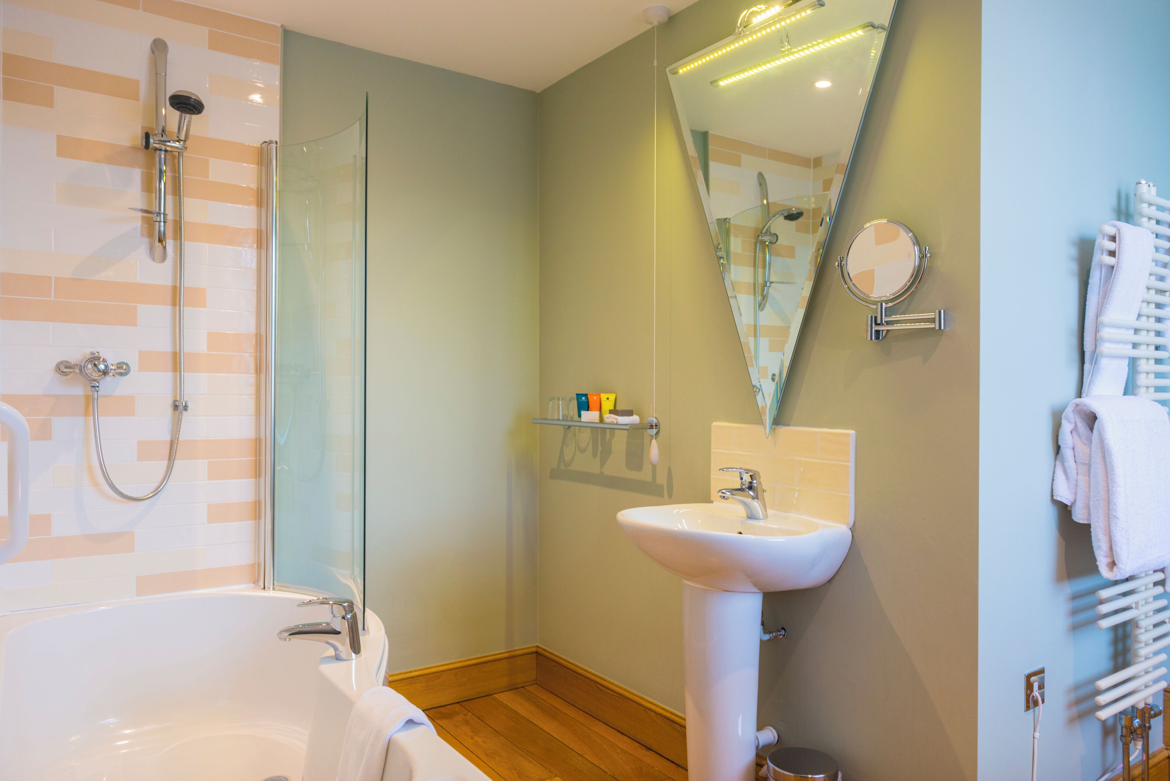 A bathroom with a bathtub, shower, sink, and a mirror.
