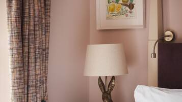 Une chambre d’hôtel avec un lit, une lampe, un tableau au mur et un rideau.
