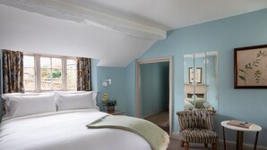 A bedroom with a large bed, a chair, a small table, and a mirror on the wall. - The Beeley Inn  (Matlock)
