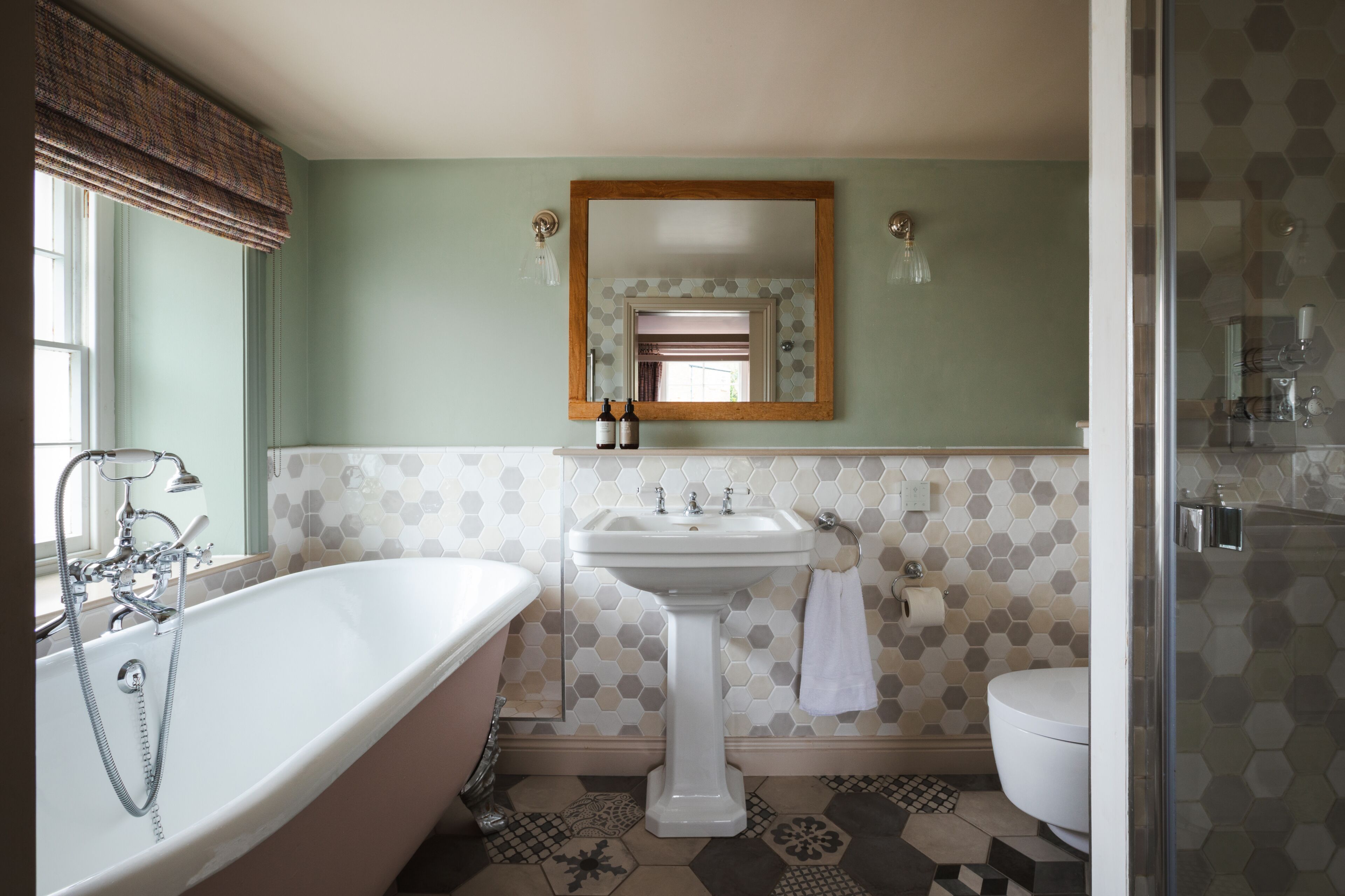 A bathroom with a freestanding bathtub, a pedestal sink, and a toilet.