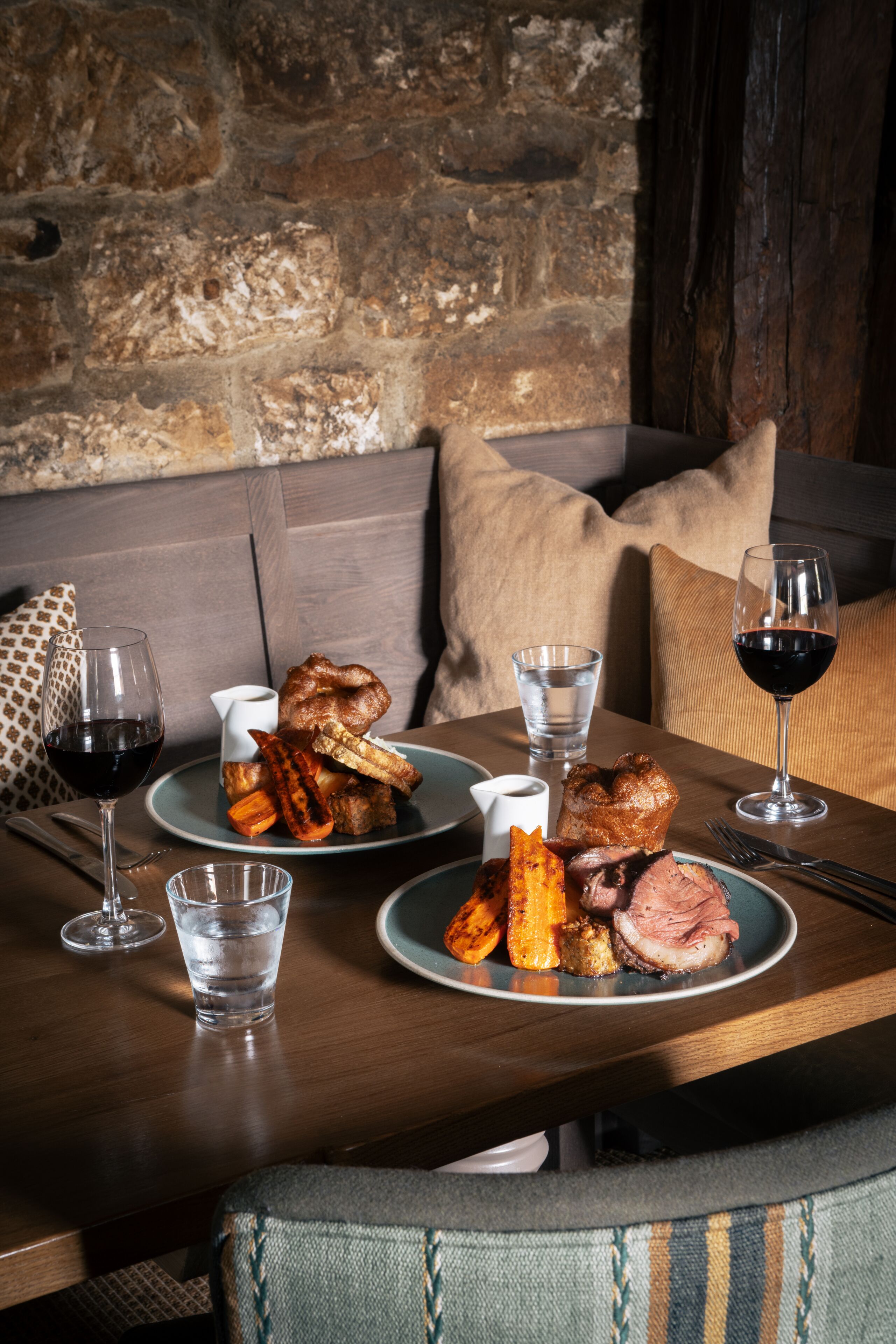 A dining table with plates of food, glasses of wine, and cutlery.