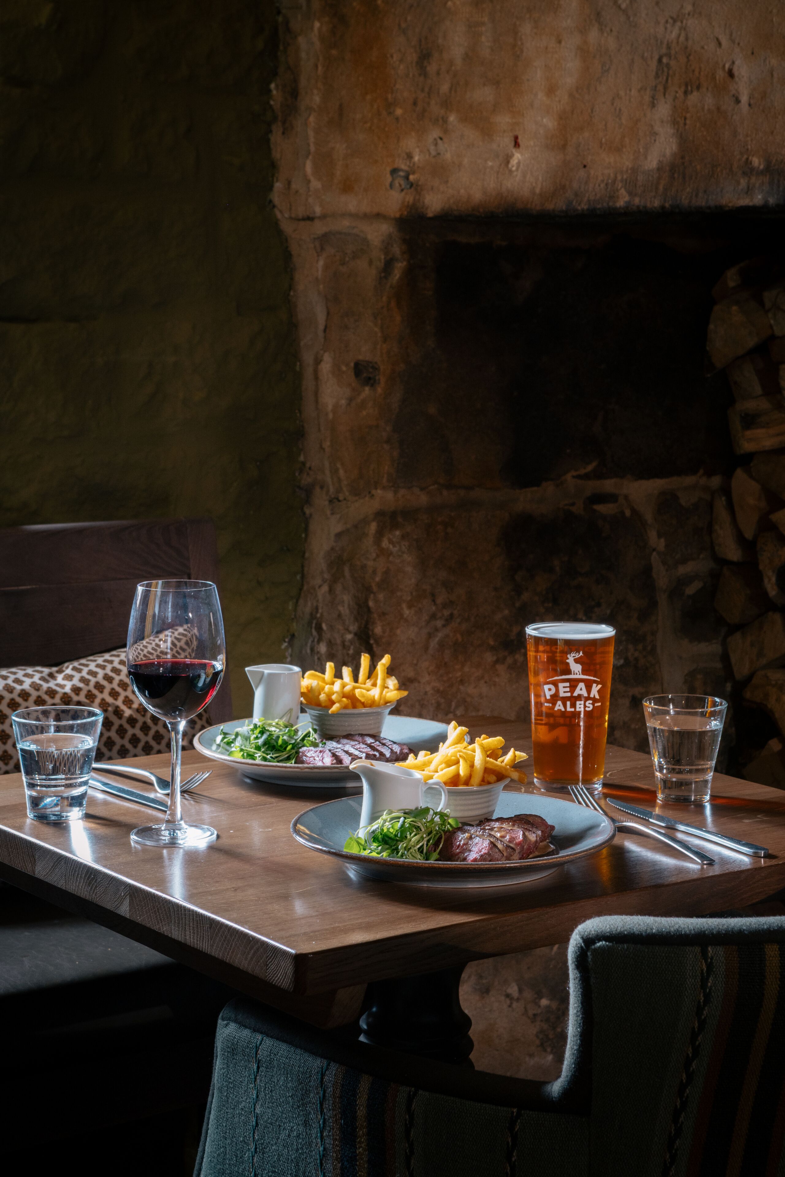 Una mesa de comedor con platos de comida, vasos de bebidas y cubiertos.