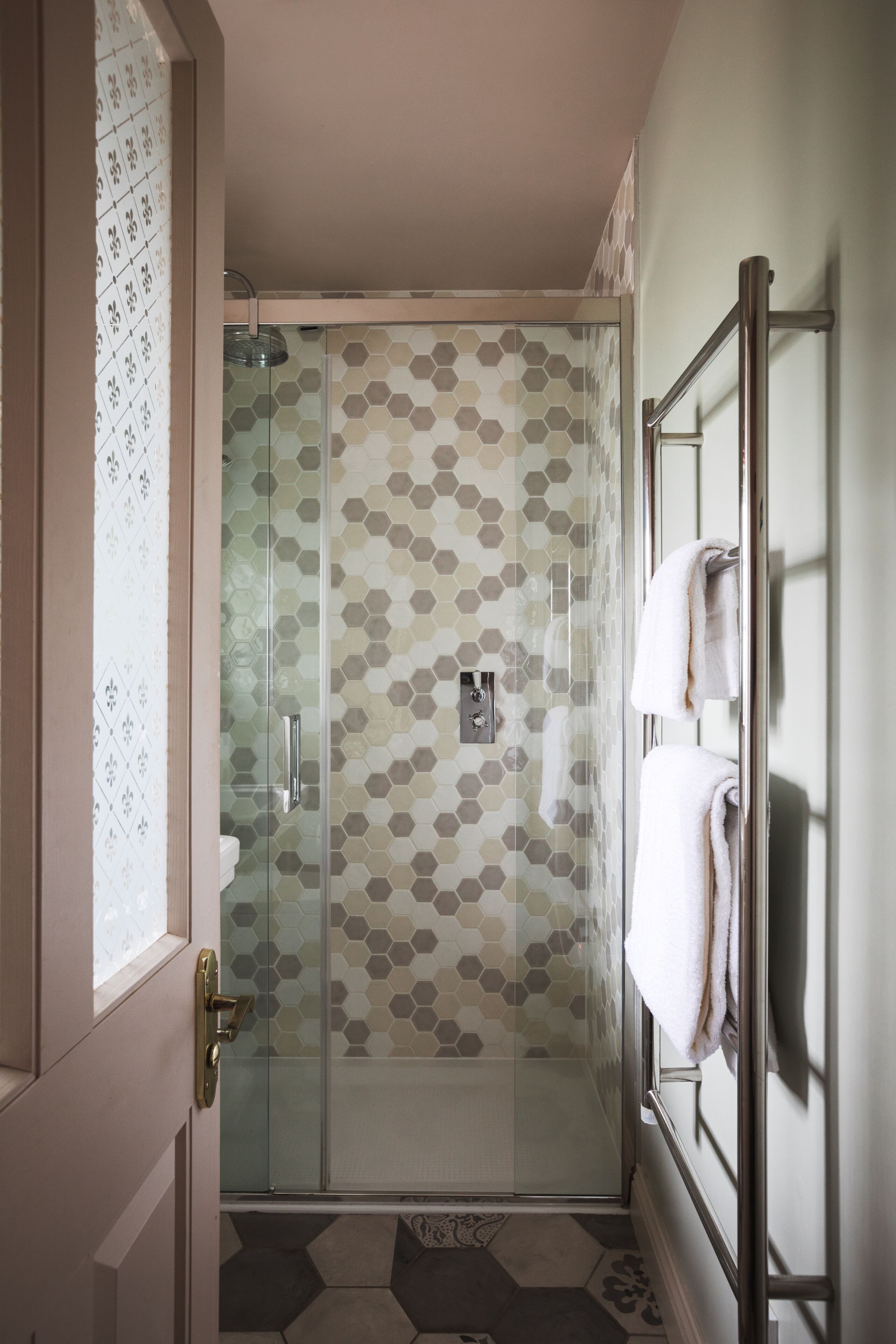 A glass-enclosed shower with a hexagonal tile pattern.