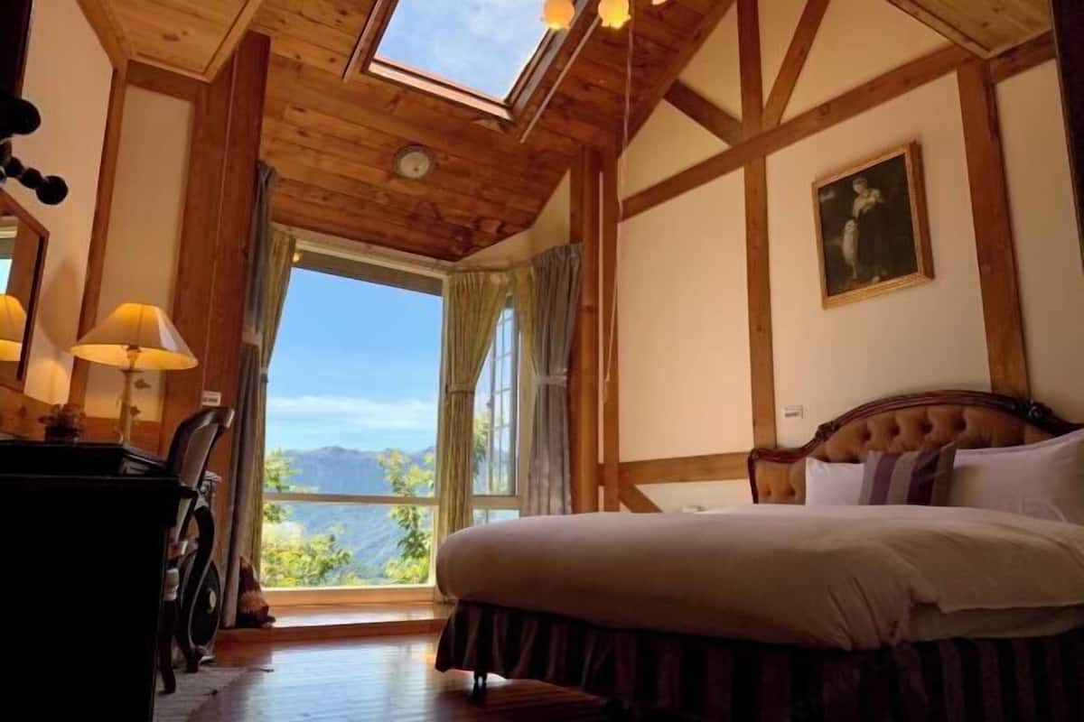 Ein Schlafzimmer mit Bett, Schreibtisch, Stuhl, Fenster mit Aussicht und einem Bild an der Wand.