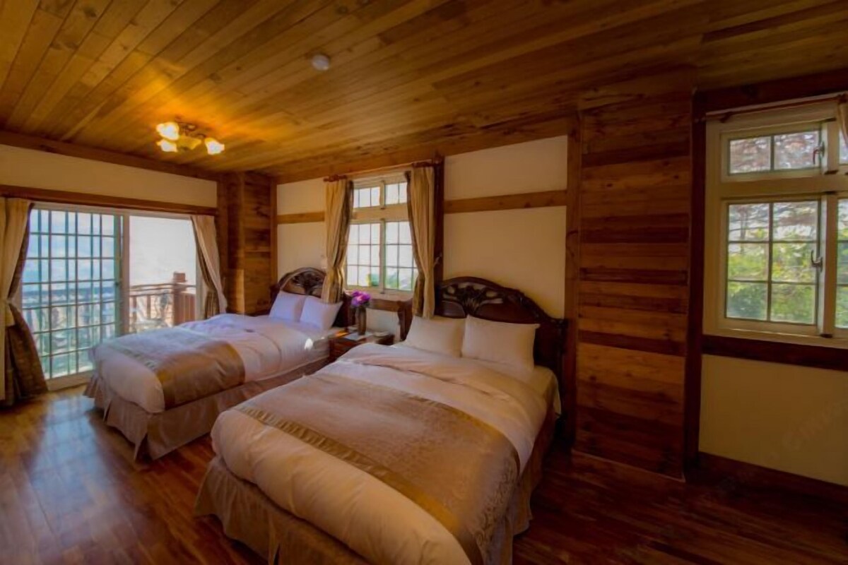 Une pièce de style cabane en bois, avec deux lits, un plafond en bois et de grandes fenêtres.