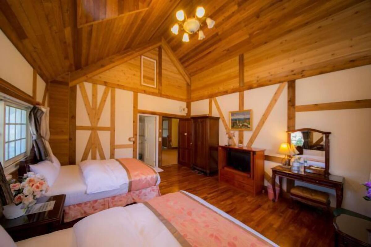 Ein gemütlicher Holzraum mit zwei Betten, einem Schreibtisch und einem Fernseher.