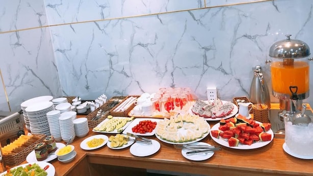 A buffet table with various food items and a beverage dispenser. - Hoa De Nhat Hotel (Ho Chi Minh City)
