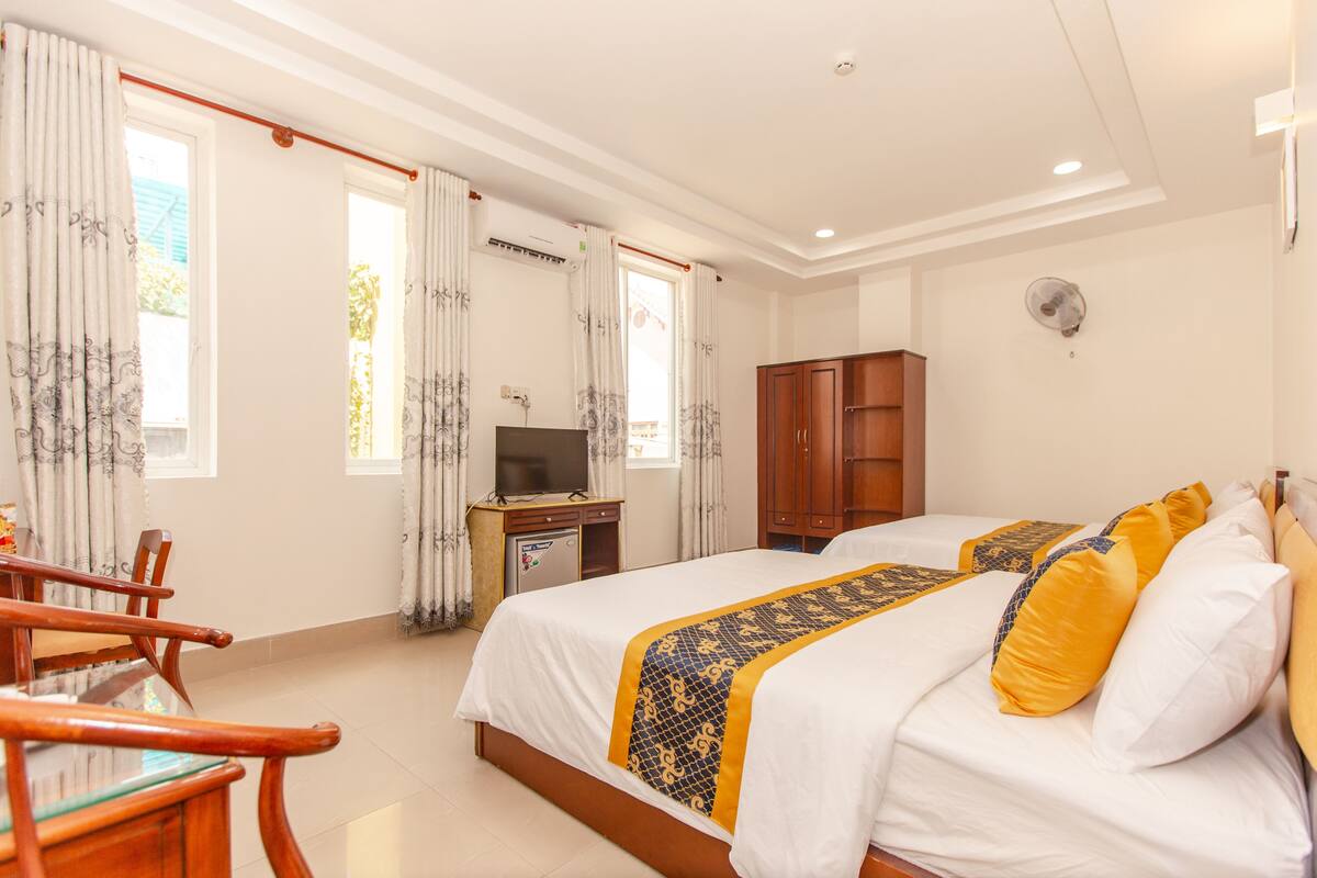 Habitación de hotel con cama, escritorio con televisor, armario y zona de comedor con sillas.