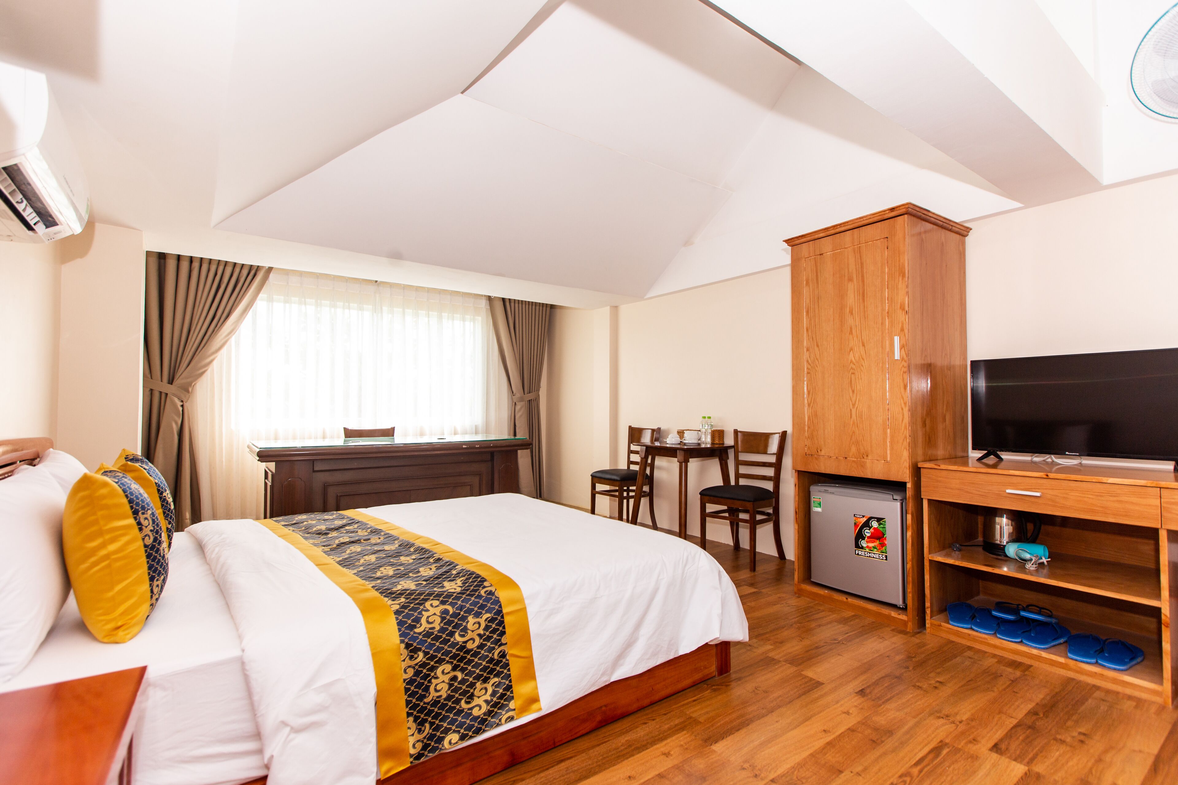 Una camera d'hotel con un letto, una scrivania, una televisione e un mini-frigorifero.