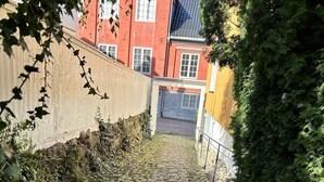 A cobblestone path leading to a red building with white windows. - Toldgaarden Gjestegaard (Larvik)