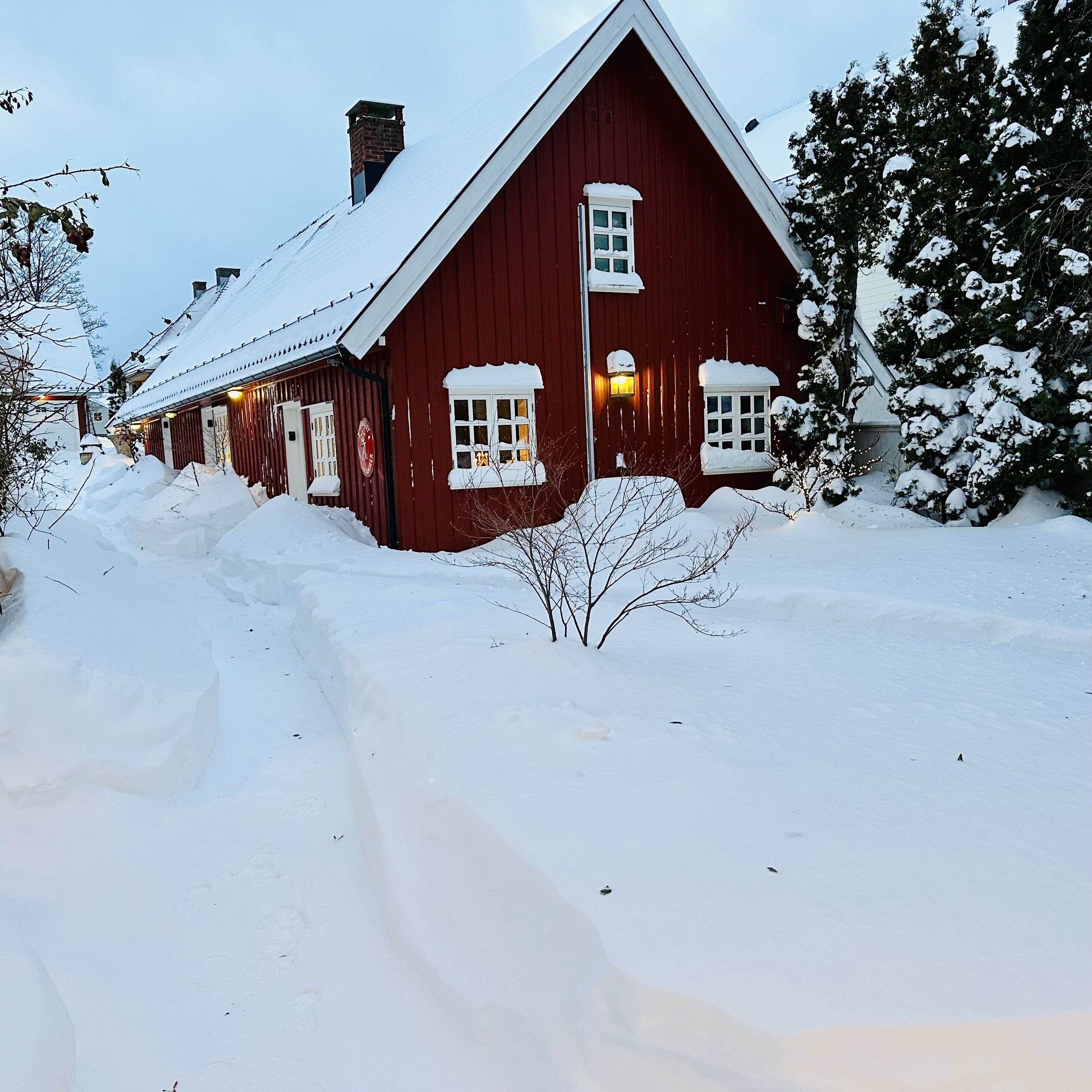 Un edificio de madera roja con ventanas cubiertas de nieve y una chimenea.