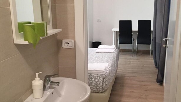A bathroom with a sink, mirror, and green soap dispensers. - Elite Loreto Milano (Milan)
