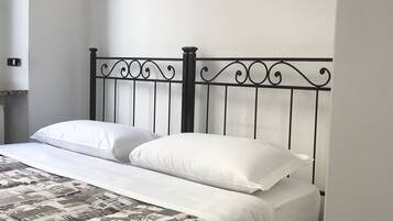 Un letto con struttura in metallo, biancheria da letto bianca e copripiumino fantasia.