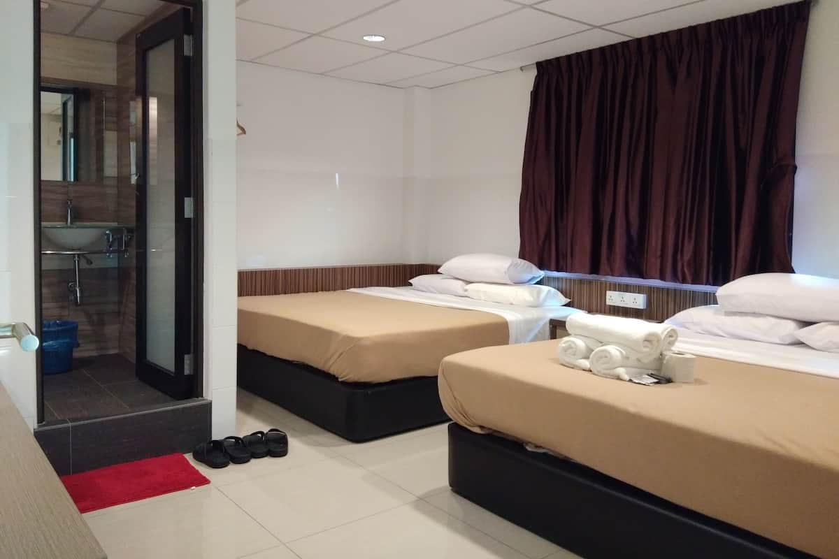 A hotel room with two beds, a bathroom, and a red rug.