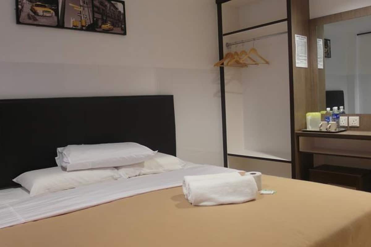 A hotel room with a bed, a bedside table, a mirror, and a wall-mounted artwork.
