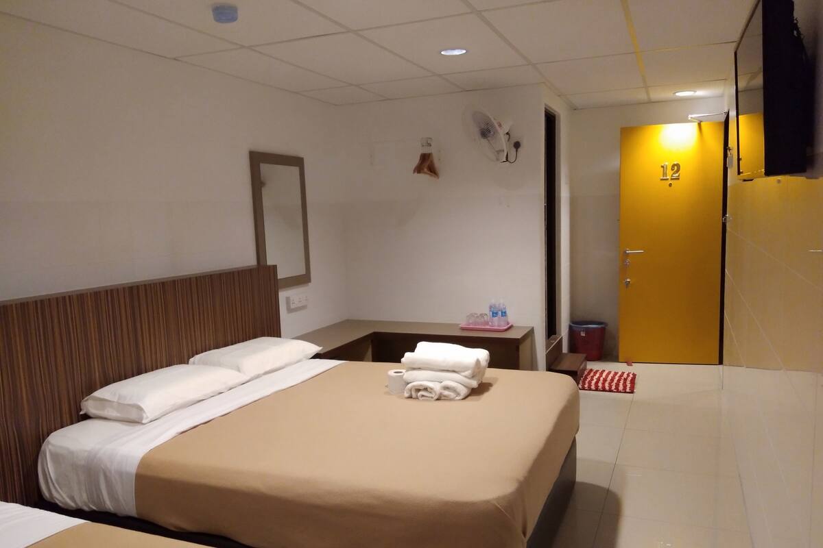 A hotel room with a bed, bedside table, and a TV mounted on the wall.