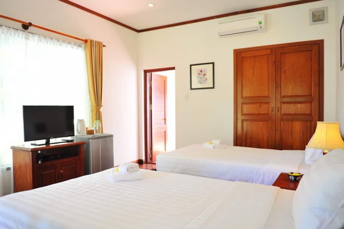 A hotel room with two beds, a TV, a desk, and a wardrobe.