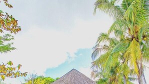 A thatched-roof gazebo with blue chairs and a bar area, surrounded by lush greenery and palm trees. - Santa Garden Resort (Phu Quoc)