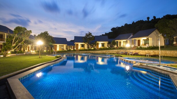 A swimming pool with a tiled deck, surrounded by buildings with a uniform architectural style. - Santa Garden Resort (Phu Quoc)