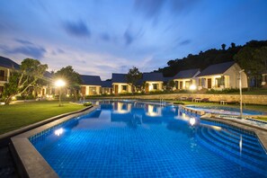 A swimming pool with a tiled deck, surrounded by buildings with a uniform architectural style. - Santa Garden Resort (Phu Quoc)