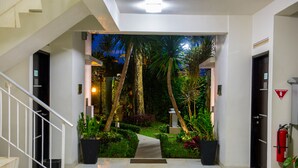 A modern hotel entrance with a staircase, a pathway leading to a lush garden, and a fire extinguisher on the wall. - D' Agape Meeting & Conference (Megamendung)