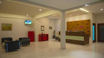 Una moderna zona de recepción con mostrador, área de estar y televisor montado en la pared.