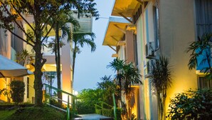 A pathway leading to a building with a modern design, surrounded by greenery and palm trees. - D' Agape Meeting & Conference (Megamendung)