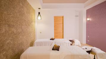 Relax in a serene spa room with two treatment beds, each equipped with a convenient tray for essentials.
