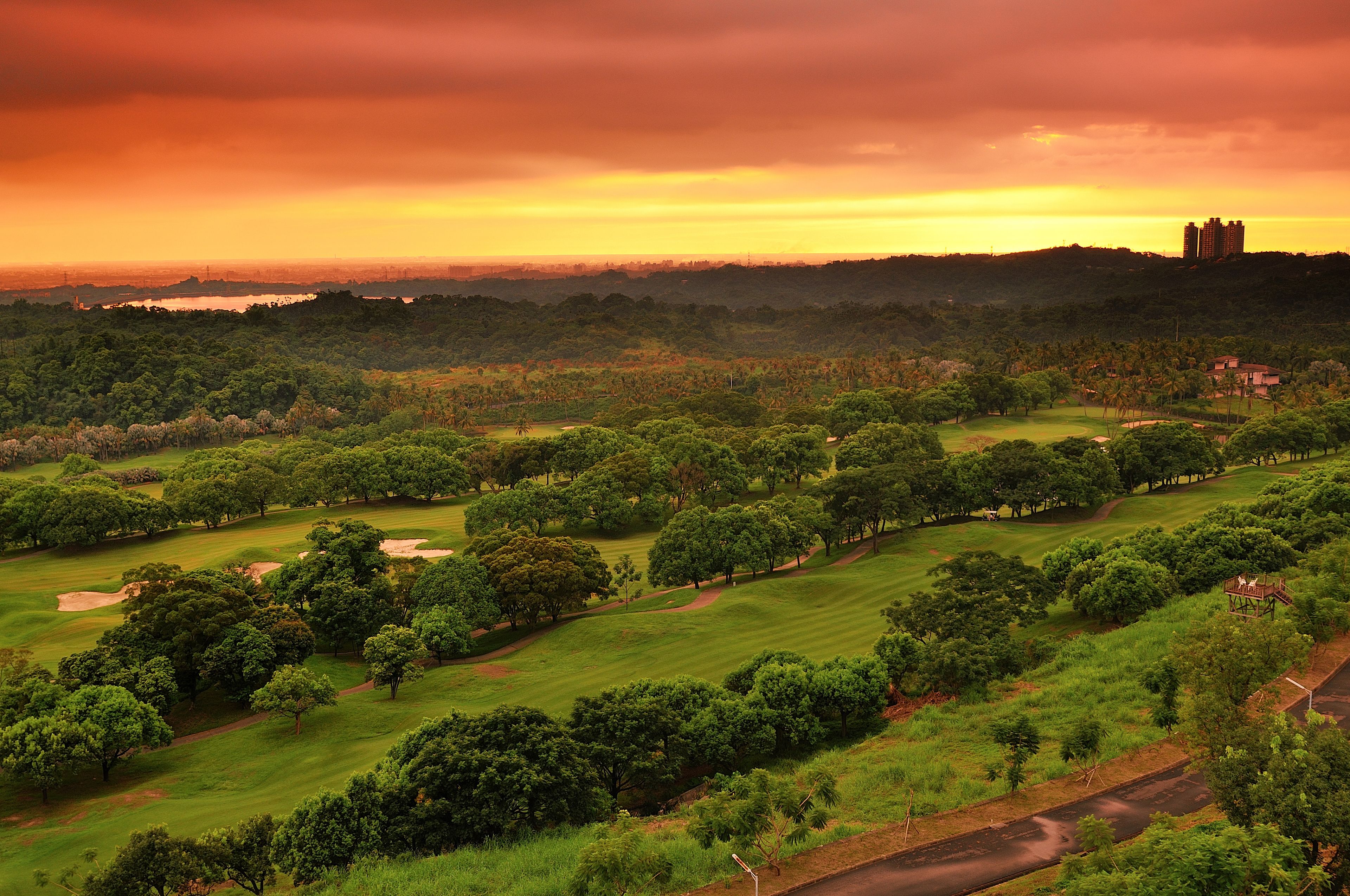 A golf course with a view of a distant city skyline and a large body of water.