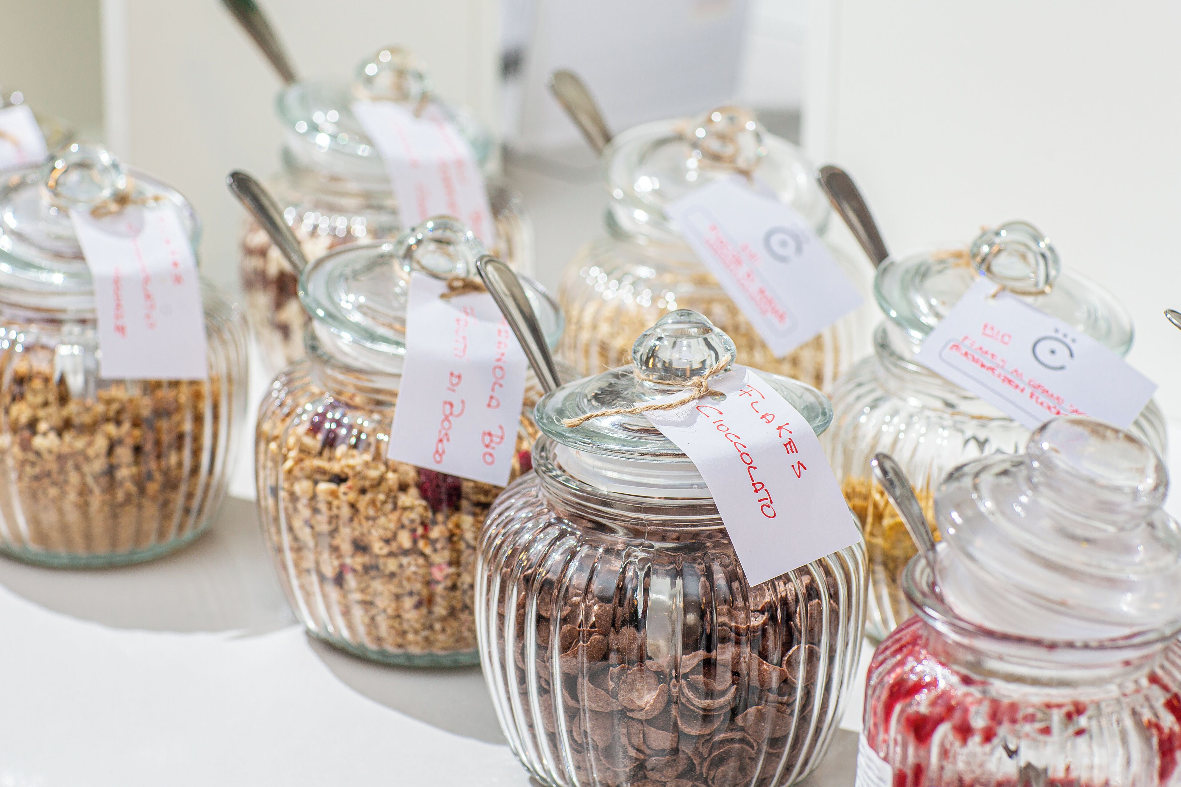 Glass jars with labels and spoons, containing various food items.