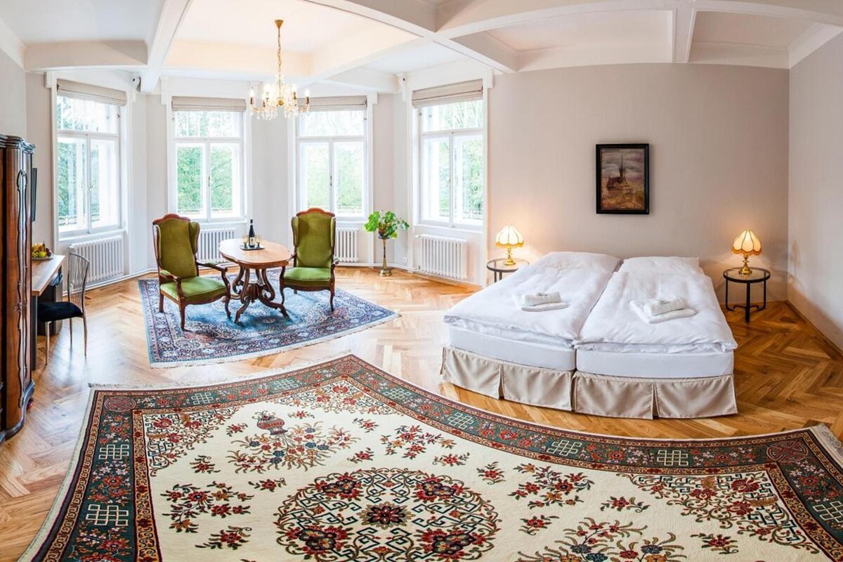 Una habitación amplia con una cama grande, un comedor con sillas y un armario de madera.