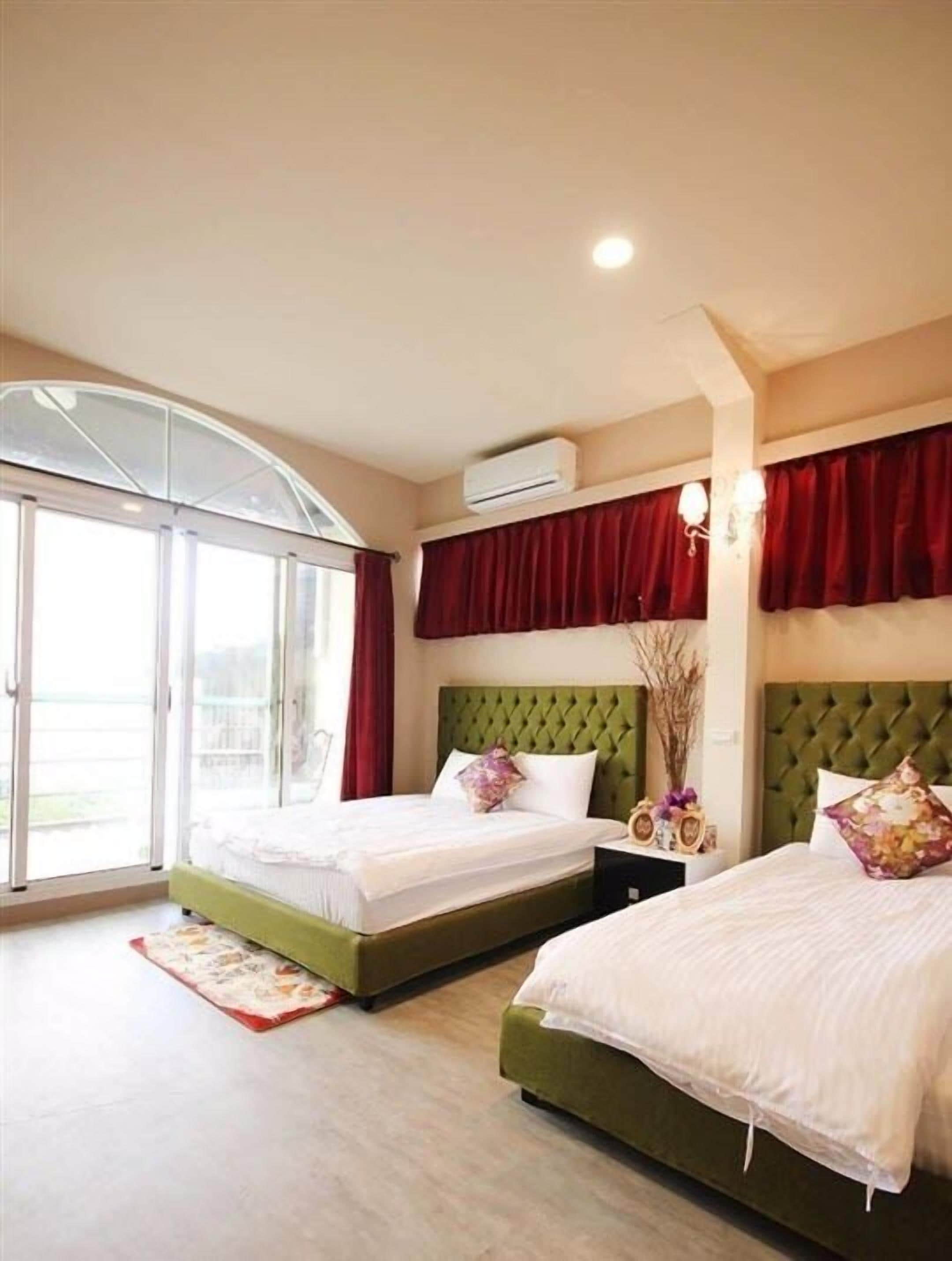 A hotel room with two beds, a large sliding glass door, and an air conditioning unit on the wall.