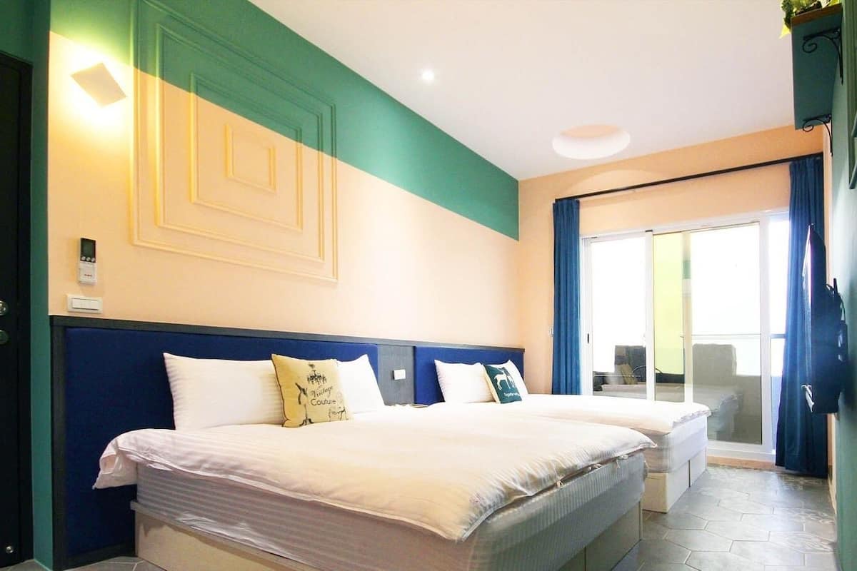 A hotel room with two beds, a large window with a view, and a door with a handle.
