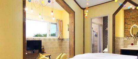 Habitación de hotel con una cama grande, televisión, baño y zona de comedor.