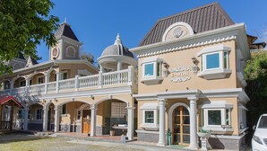 Ein Gebäude im klassischen Baustil, mit einem Balkon, Bogenfenstern und einem Schild mit der Aufschrift 'E-MOH'.