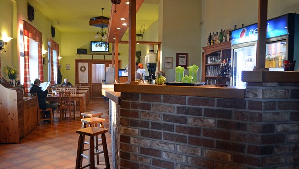 A restaurant with brick walls, wooden furniture, and a bar area.